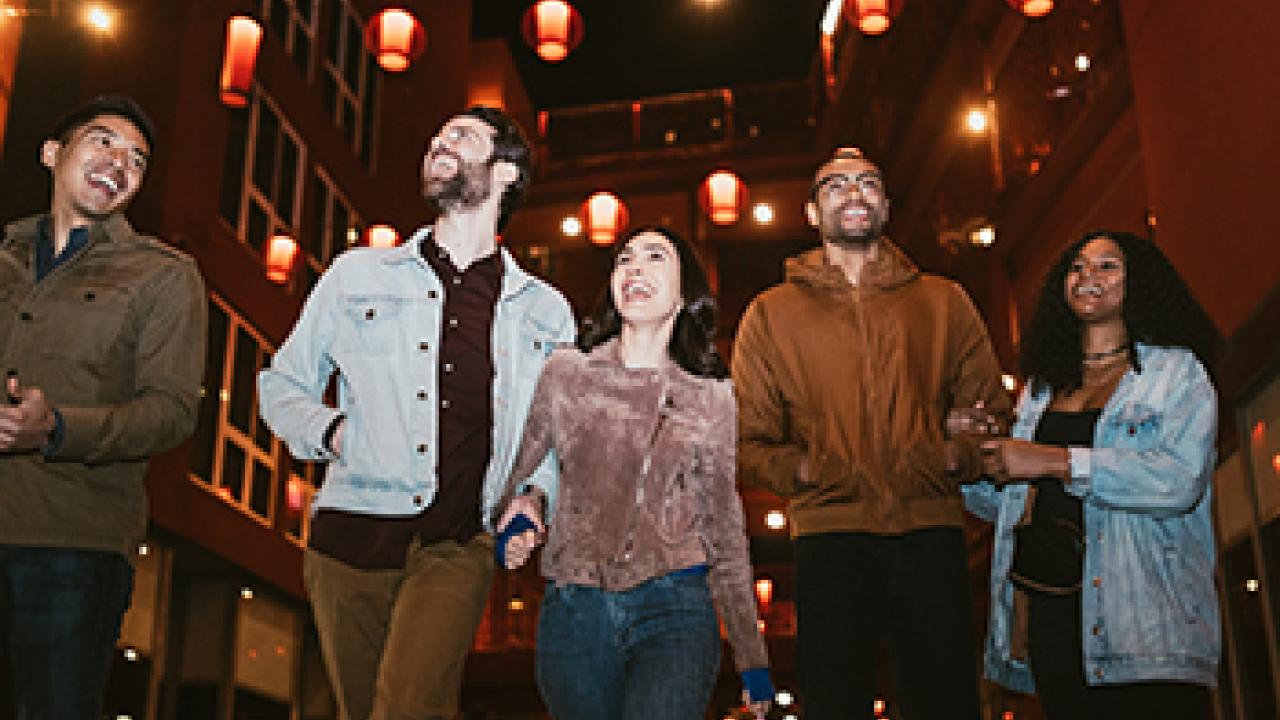 group of friends walking and laughing in an urban area outside at night