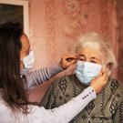 younger woman putting face mask on older woman