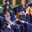 man in graduation attire and uc davis face mask