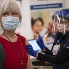 woman in mask receiving vaccine shot